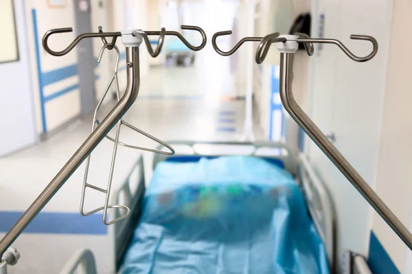 Uma cama de hospital vago no corredor com suportes conta-gotas . — Fotografia de Stock