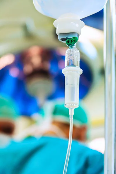 IV drip in operation room with surgeons — Stock Photo, Image