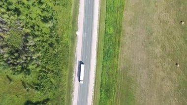 Kırsal bölgedeki hızlı kamyonların ve yazın yeşil çimlerle kaplı bataklık arazinin havadan görüntüsü.. 