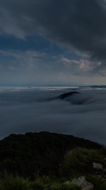 Dolunay ışığında sisli bir dağ vadisinde 9: 16 'da dikey hızlanma. Yumuşak ay ışığı bulutları delerken kara tepeler arasında dönen sis akar. Atmosferik, huzurlu gece manzarası, insan yok..