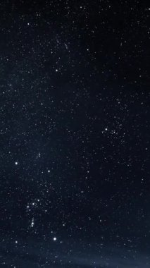 Orion 'un sayısız yıldızın arasında parladığı yıldızlarla dolu bir gece göğünün dikey hızlandırılması. Astronomi teması, parıldayan yıldız ışığı ve dingin evren titreşimleri için karanlık, kozmik bir arka plan.. 