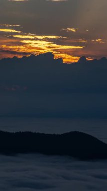 Güneşin altın ışığını gün doğumunda dramatik fırtınalı bulutlar yaz sabahı sisli bir manzaranın üzerinde şekillenirken dikey zaman dilimi yansıtıyor. Fırtınalı hava arka planı.