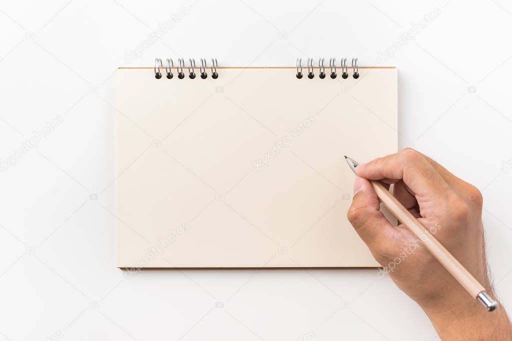 Design concept - Top view of kraft spiral notebook, blank page and man's hand holding wood pen isolated on white background for mockup