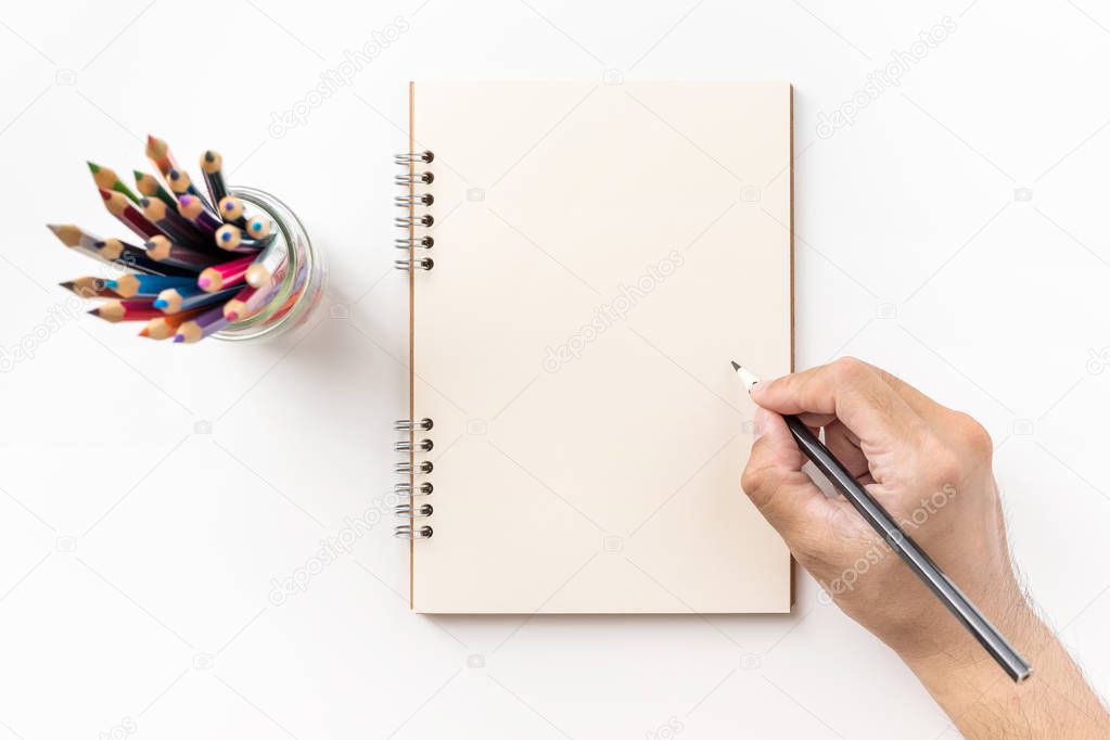 Design concept - Top view of kraft spiral notebook, blank page, pen holder and man's hand holding color pen isolated on white background for mockup