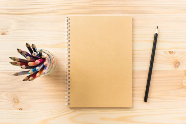 Tasarım konsepti - mockup için ahşap masa arka plan üzerinde kraft spiral defter, kalem sahibi ve ahşap kalem üstten görünüm