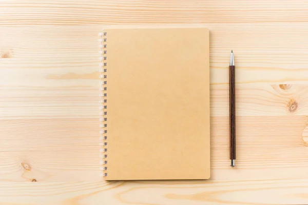 Design concept - Top view of black kraft spiral notebook and wood mechanical pencil on wood table background for mockup