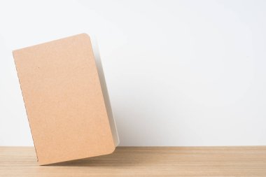 Kavram - kayan kraft defter ve mockup için ahşap masaüstü ve beyaz arka plan üzerine açık görünüm Tasarla
