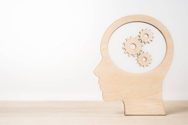 İş ve tasarım konsepti - Ahşap ahşap masaüstü ve beyaz arka plan üzerinde gearwheel kafayla siluet dostum