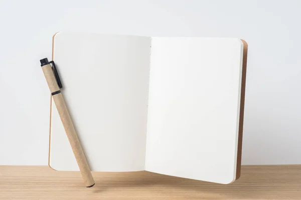 设计理念 浮动卡夫笔记本的前视图和木制桌面和白色背景的样机 — 图库照片