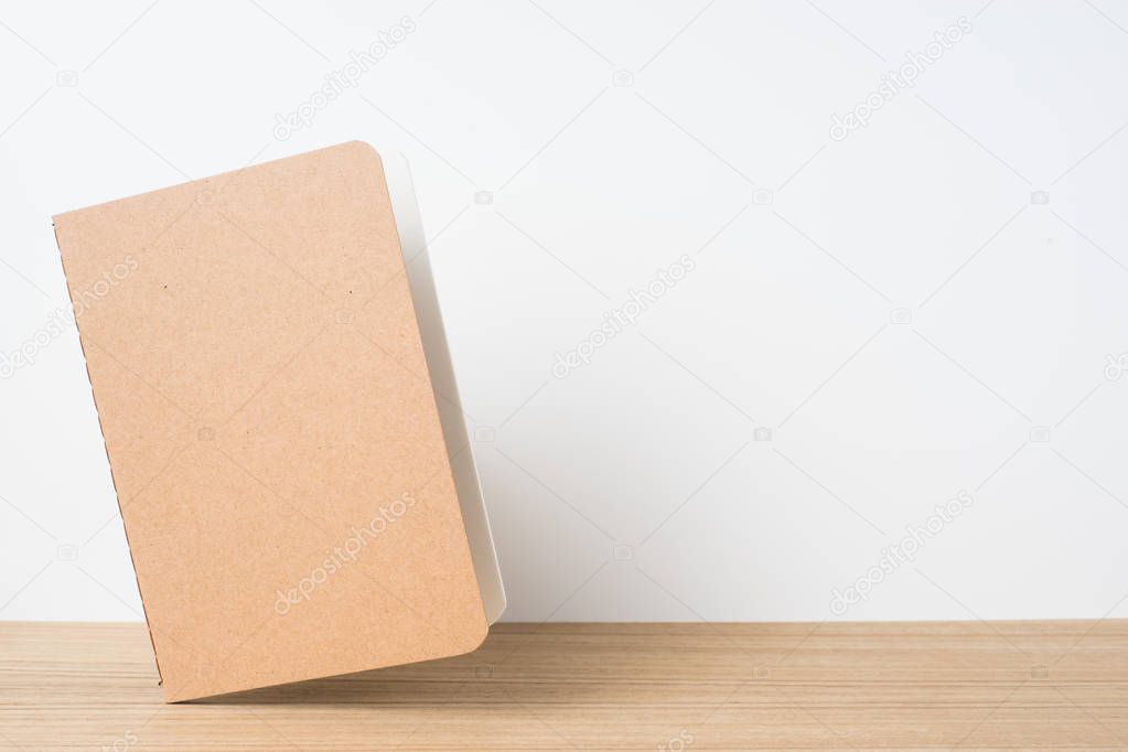 Design concept - front view of floating kraft notebook and on wooden desktop and white background for mockup