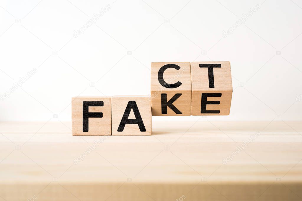 Business and design concept - surreal abstract geometric wooden cube with word FACT & FAKE concept on wood floor and white background