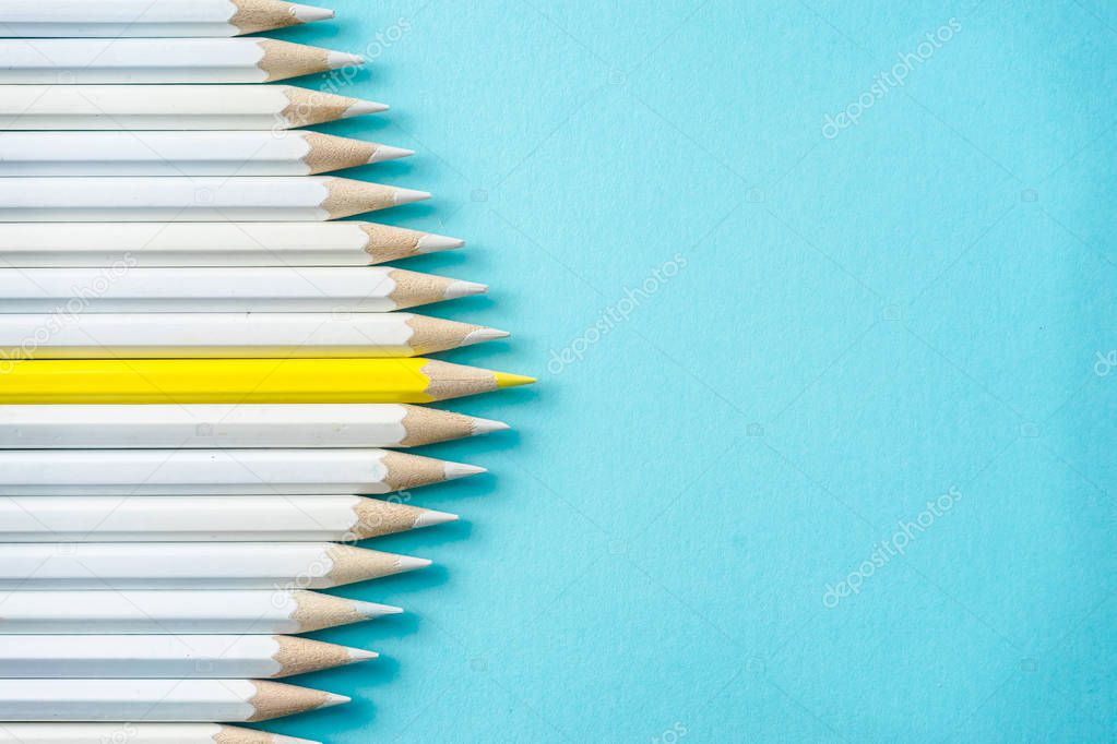 Business concept - lot of white pencils and one color pencil on blue paper background. It's symbol of leadership, teamwork, united and communication.