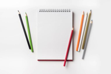 Tasarım konsepti - in kırmızı spiral defter üstten görünüm ve birçok renk kalem koleksiyonu mockup için beyaz arka plan üzerinde izole