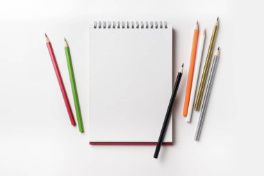 Tasarım konsepti - in kırmızı spiral defter üstten görünüm ve birçok renk kalem koleksiyonu mockup için beyaz arka plan üzerinde izole