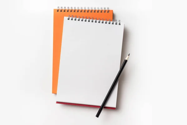 デザイン コンセプト オレンジと赤のスパイラル ノートと色鉛筆コレクションがモックアップの白い背景で隔離の平面図 — ストック写真