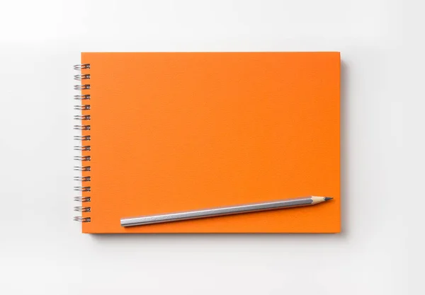 デザイン コンセプト オレンジ色のスパイラル ノートと色鉛筆コレクションがモックアップの白い背景で隔離の平面図 — ストック写真