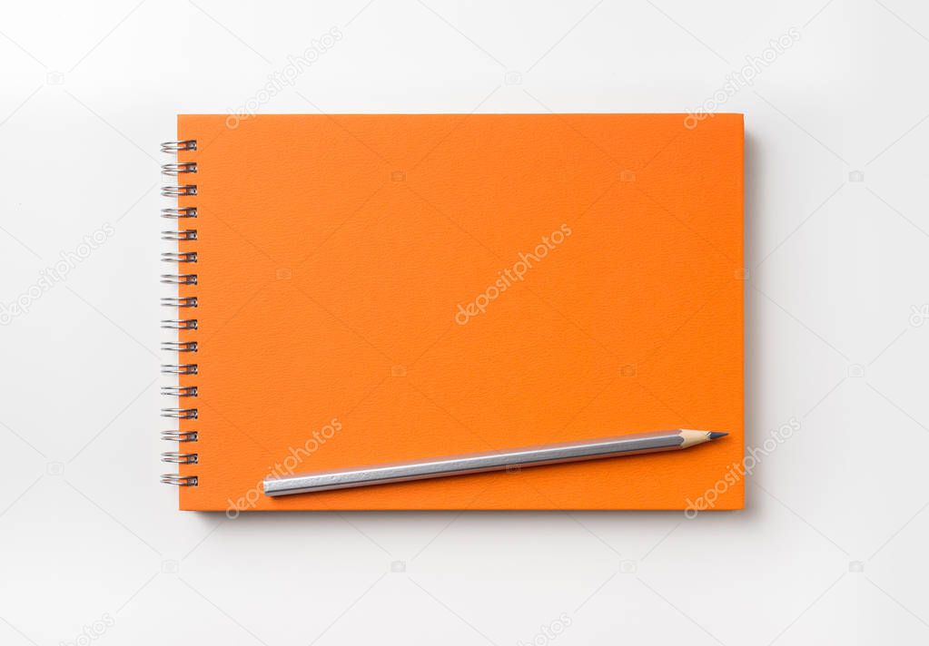 Design concept - Top view of orange spiral notebook and color pencil collection isolated on white background for mockup