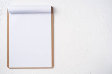 Mockup için beyaz arka plan üzerinde izole kahverengi pano üzerinde beyaz A4 çevrilmiş kağıt üst görünümü.