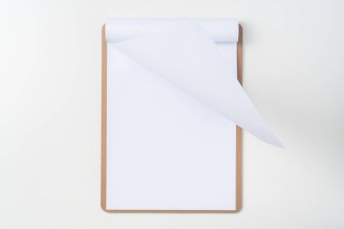 Mockup için beyaz arka plan üzerinde izole kahverengi pano üzerinde beyaz A4 çevrilmiş kağıt üst görünümü.