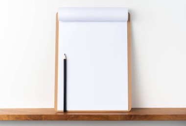 Mockup için beyaz arka plan üzerinde rafta kalem ile kahverengi pano üzerinde A4 çevrilmiş kağıt.
