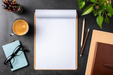 Siyah arka plan üzerinde spiral defter, saksı bitki, gözlük, kahve, kalem ve çanta ile kopya alanı.