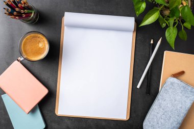 Siyah arka plan üzerinde spiral defter, saksı bitki, gözlük, kahve, kalem ve çanta ile kopya alanı.