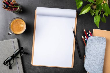 Siyah arka plan üzerinde spiral defter, saksı bitki, gözlük, kahve, kalem ve çanta ile kopya alanı.