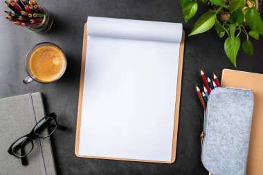 Siyah arka plan üzerinde spiral defter, saksı bitki, gözlük, kahve, kalem ve çanta ile kopya alanı.