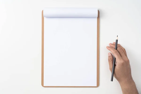 Top view of man hand holding pencil on white A4 flipped paper with brown clipboard isolated on white background.