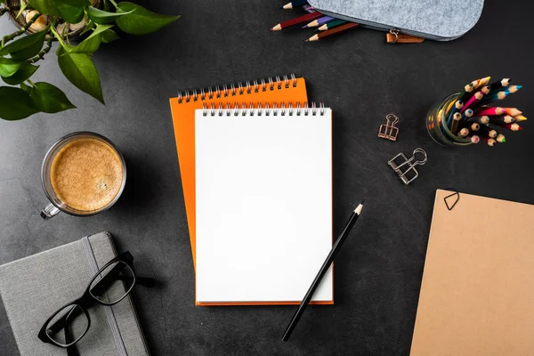 Spiral defterler, saksı bitki, gözlük, kahve, kalem, çanta ve maket için siyah arka plan üzerinde pimleri.
