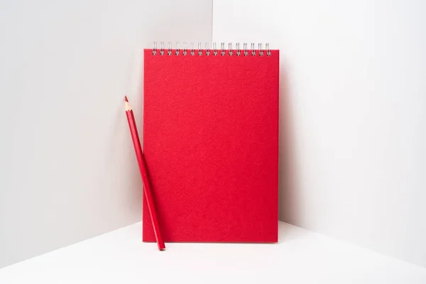 白い背景に赤い鉛筆が付いた赤いスパイラルノートブック — ストック写真