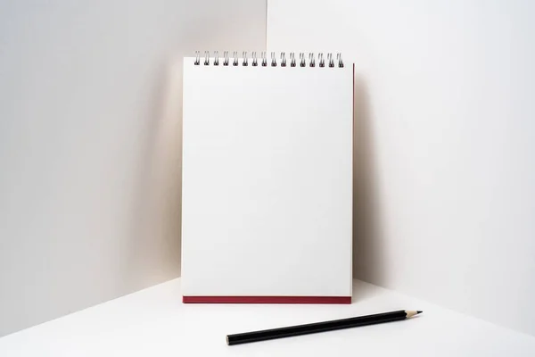 红色螺旋笔记本与黑色铅笔在白色背景模型 — 图库照片