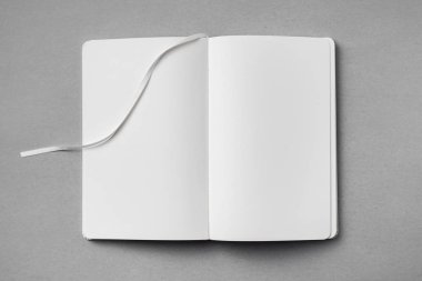 Mockup için gri arka plan üzerinde şerit yer imi ile açılan beyaz not defteriüst görünümü.
