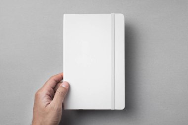 Tasarım konsepti - gri arka planda elastik bantlı beyaz dizüstü bilgisayarı tutan en iyi görünüm erkek el.