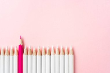 İş ve tasarım konsepti - beyaz kalem ve pembe kağıt arka plan üzerinde bir renk kalem çok. Liderlik, takım çalışması, başarı ve benzersiz sembolü.