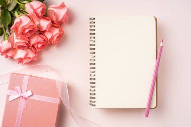 Pembe gül buketi, hediye kutusu, beyaz defter, pembe arka plan üzerine kalem