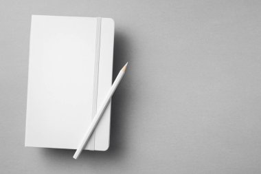 Gri arka planda tahta kalemi olan beyaz defter..