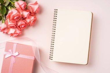 Pembe gül buketi, hediye kutusu, pembe arka plan üzerine beyaz defter