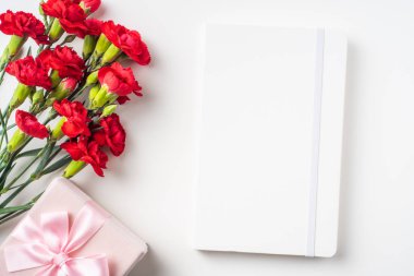 Pik hediye kutusu ve beyaz arka plan üzerinde izole beyaz dizüstü bilgisayar ile kırmızı karanfil demet üst görünümü