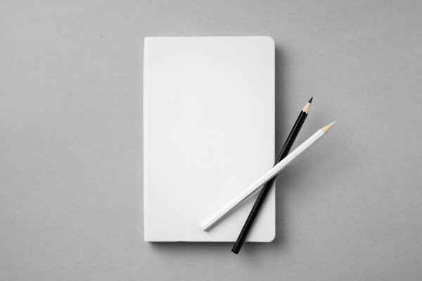 Design concept - top view of white notebook with wooden pencils on grey background for mockup.