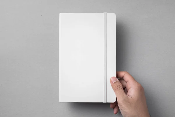 设计理念 顶视图男性手拿着白色笔记本与弹性带在灰色背景 — 图库照片