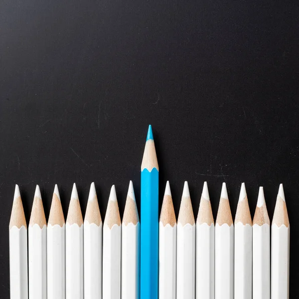 İş ve tasarım konsepti - beyaz kalem ve siyah arka plan üzerinde bir renk kalem çok. Liderlik, takım çalışması, başarı ve benzersiz sembolü.