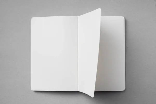 デザインコンセプト モックアップ用の灰色の背景に空白の開いたページ ターン 反転した白いノートブックのトップビュー — ストック写真