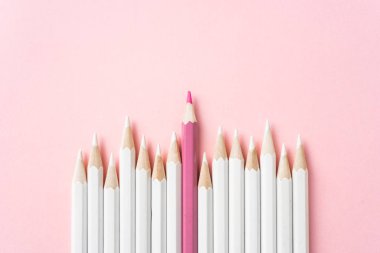 İş ve tasarım konsepti - beyaz kalem ve pembe kağıt arka plan üzerinde bir renk kalem çok. Liderlik, takım çalışması, başarı ve benzersiz sembolü.
