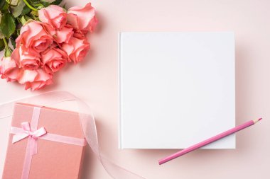 Pembe gül buketi, hediye kutusu, beyaz defter, pembe arka plan üzerine kalem
