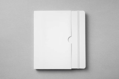 Elastik bantlı kapalı beyaz dizüstü bilgisayar, mockup için gri arka plan kılıfı.
