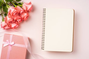 Pembe gül buketi, hediye kutusu, pembe arka plan üzerine beyaz defter