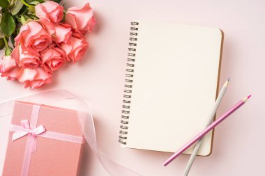 Pembe gül demet, hediye kutusu, kalem ve pembe arka plan üzerinde vintage kurdele ile defter.