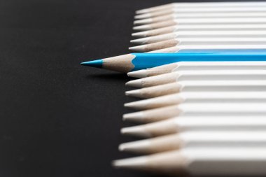 İş ve tasarım konsepti - beyaz kalem ve siyah arka plan üzerinde bir renk kalem çok. Liderlik, takım çalışması, başarı ve benzersiz sembolü.