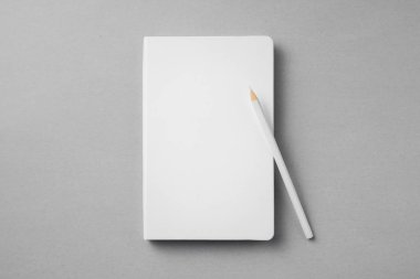 Gri arka planda tahta kalemi olan beyaz defter..